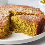 A slice of 3 Ingredient Pistachio Cake topped with nuts and vibrant green color.