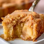 Slice of homemade Apple Dapple Cake on a plate with apples and cinnamon