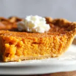 Slice of homemade sweet potato pie with whipped cream on top