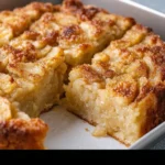 A slice of Parisian Apple Cake topped with powdered sugar and fresh apples.