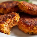 Crispy fried salmon patties served on a plate with lemon and herbs