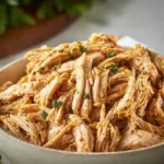 Crockpot shredded chicken breast dish served on a plate with herbs