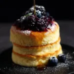 Fluffy Japanese soufflé pancakes stacked on a plate with syrup.
