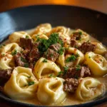 Creamy cheesesteak tortellini in provolone sauce with garnishes
