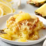 Delicious Lemon Pineapple Dump Cake served on a white plate with a yellow background