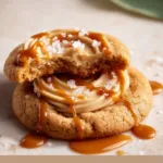 Delicious salted caramel cheesecake cookies on a plate, topped with caramel drizzle.