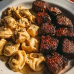 Delicious Garlic Butter Steak Bites served with creamy Alfredo tortellini on a plate.