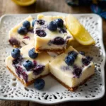 Delicious blueberry cheesecake bars topped with fresh blueberries.