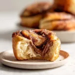 Freshly baked homemade cinnamon rolls with icing on a rustic wooden table