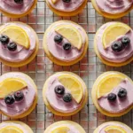 Lemon cookies with vibrant blueberry frosting on a white plate