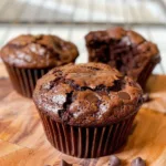 Freshly baked brownie muffins with chocolate chunks on a cooling rack.